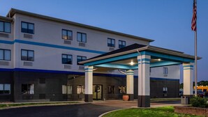 A multi-story hotel with a covered entrance, a flagpole, and a parking lot. - Days Inn by Wyndham Collinsville/St. Louis (Collinsville)