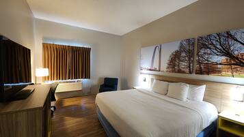 A hotel room with a large bed, a desk with a TV, a chair, and a window with curtains.
