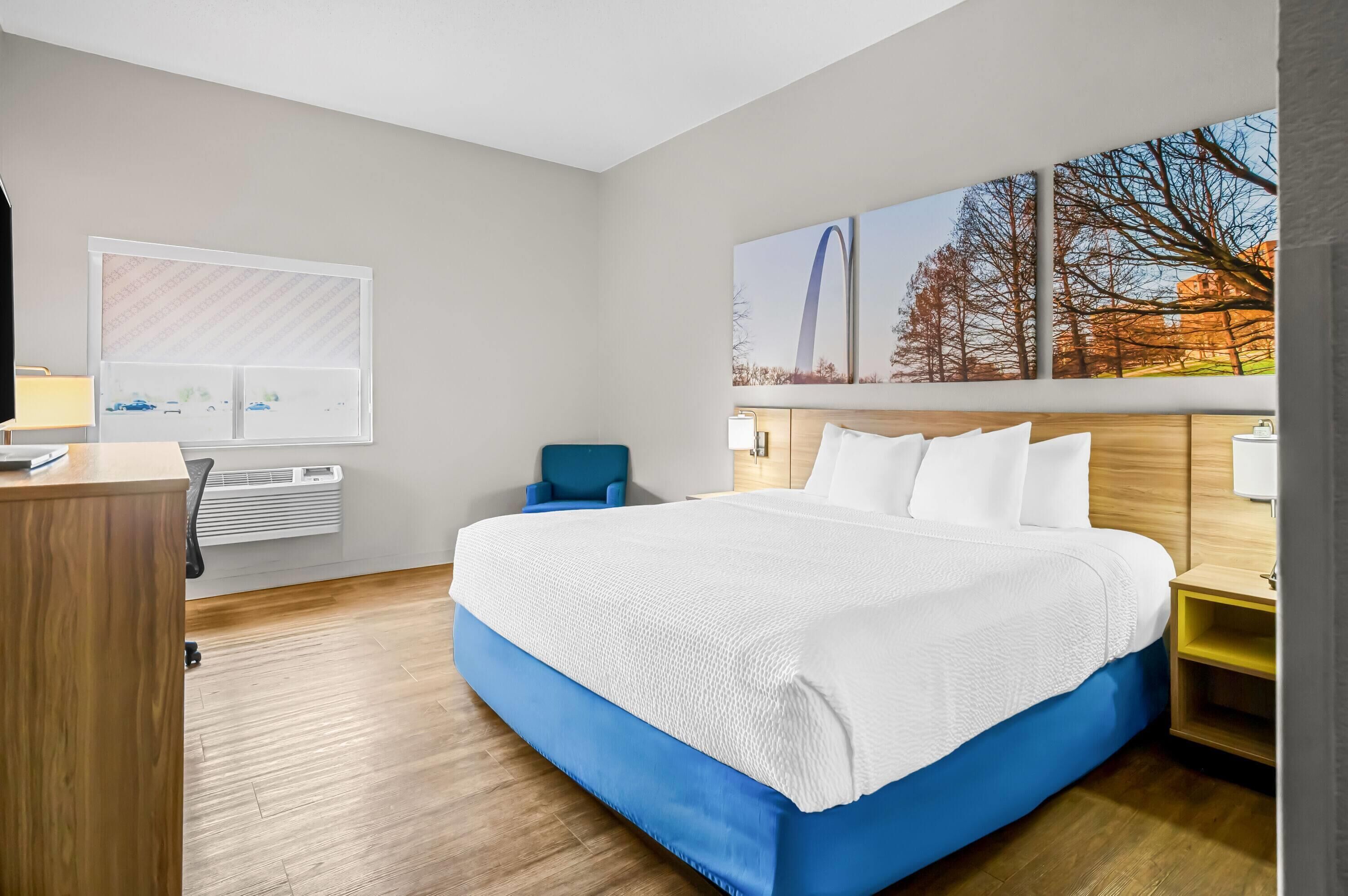 Habitació d'hotel moderna amb un llit gran, un escriptori i una finestra amb persianes.