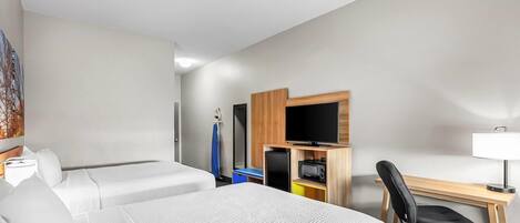 A hotel room with two beds, a desk with a computer, a TV, and a chair.