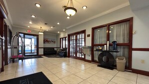 Un hall d’hôtel comprenant un comptoir d’accueil, un espace salon et une grande fenêtre avec des rideaux.