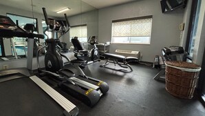 Une salle de sport équipée de tapis de course, de vélos elliptiques et d’un banc de musculation.