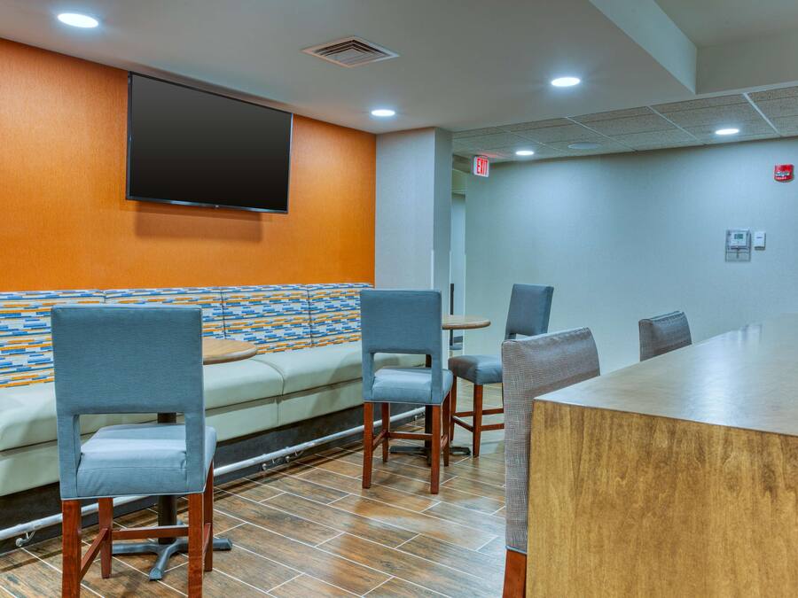 A conference room with a long table, several chairs, a sofa, and a television mounted on the wall.