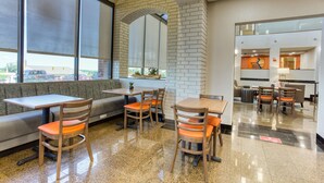 A restaurant with a brick wall, large windows, and a seating area with tables and chairs.