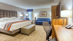 A hotel room with a large bed, a desk, a chair, and a television.