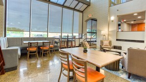 A spacious indoor area with a large table and chairs, a sofa, and a staircase leading to an upper level.