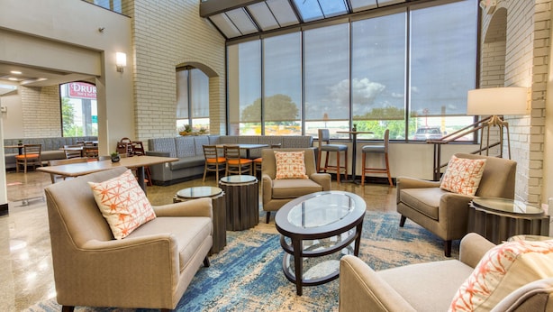 A spacious lobby with a high ceiling, large windows, and a variety of seating options including sofas and chairs.