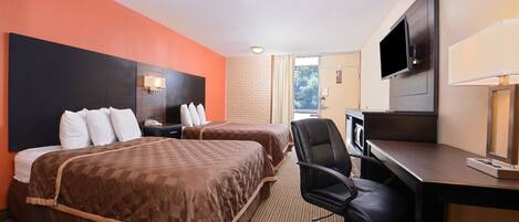 A hotel room with two beds, a desk, a chair, a television, and a window with curtains.
