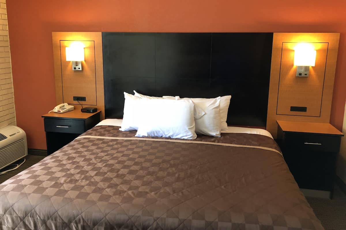 Habitación de hotel con una cama grande, dos mesitas de noche, un teléfono y lámparas fijadas a la pared.