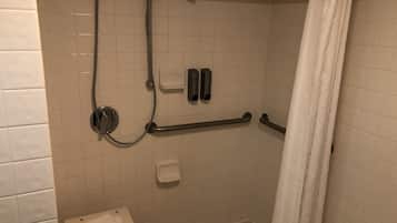 A shower with a handheld showerhead, a handheld soap dispenser, and a towel rack.