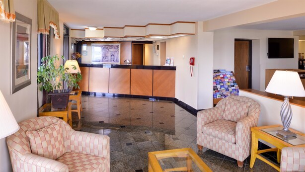 A lobby with checkered armchairs, a reception desk, a plant, and a tiled floor.