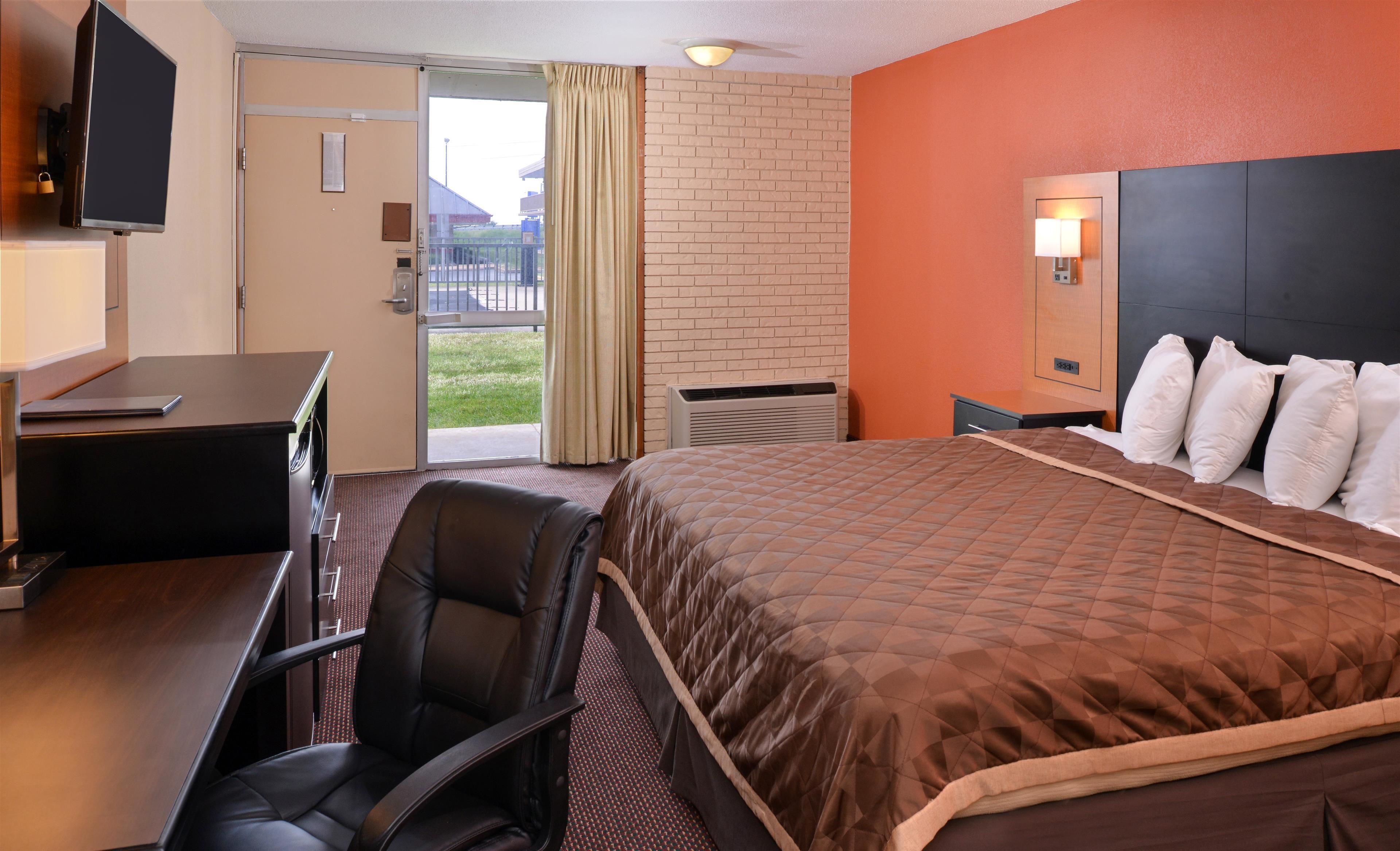 A hotel room with a bed, a desk, a chair, a television, and a view of the outdoors.