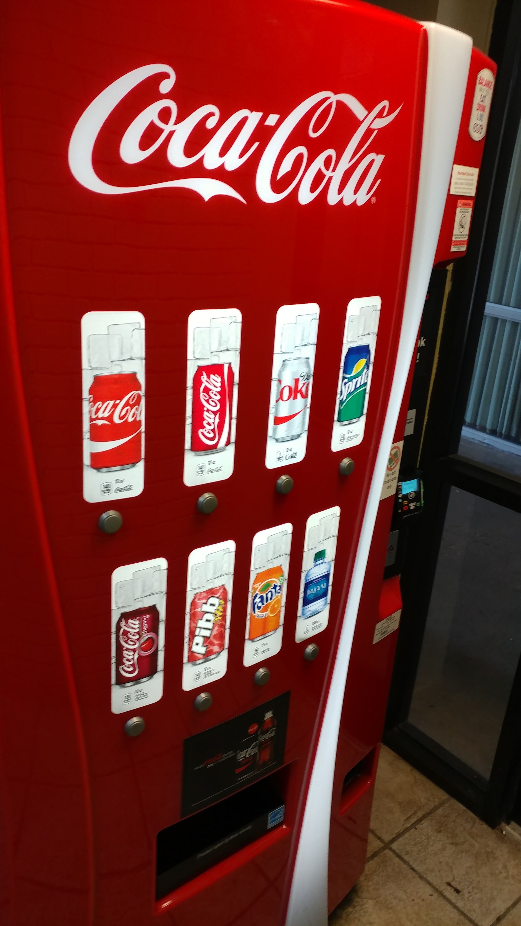 A red Coca-Cola vending machine with various drink options.