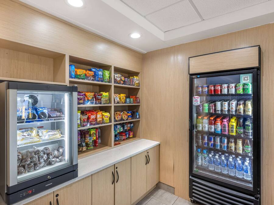 Zona de venta automática con aperitivos y bebidas, que incluye una sección refrigerada con agua embotellada y un congelador con productos envasados.