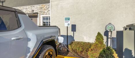 A vehicle parked in a designated area with a sign indicating reserved parking for hybrid and electric vehicles.