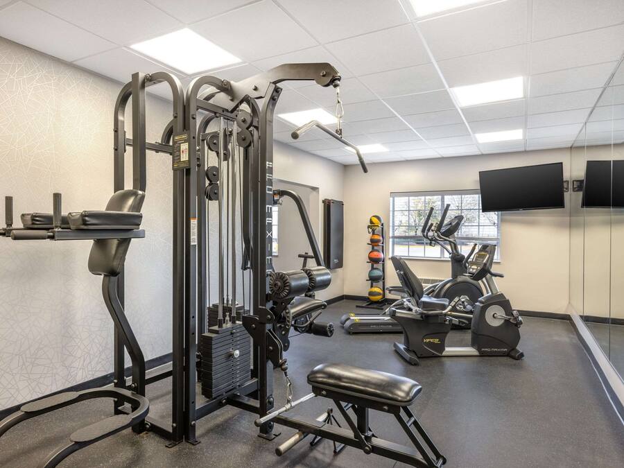 A gym with exercise equipment, a bench, and a wall-mounted TV.
