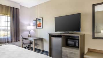 Habitación de hotel con cama, escritorio con silla, televisor, microondas y refrigerador.