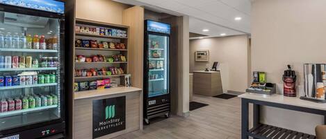 A clean, well-lit hotel lobby with vending machines, a reception desk, and a seating area.