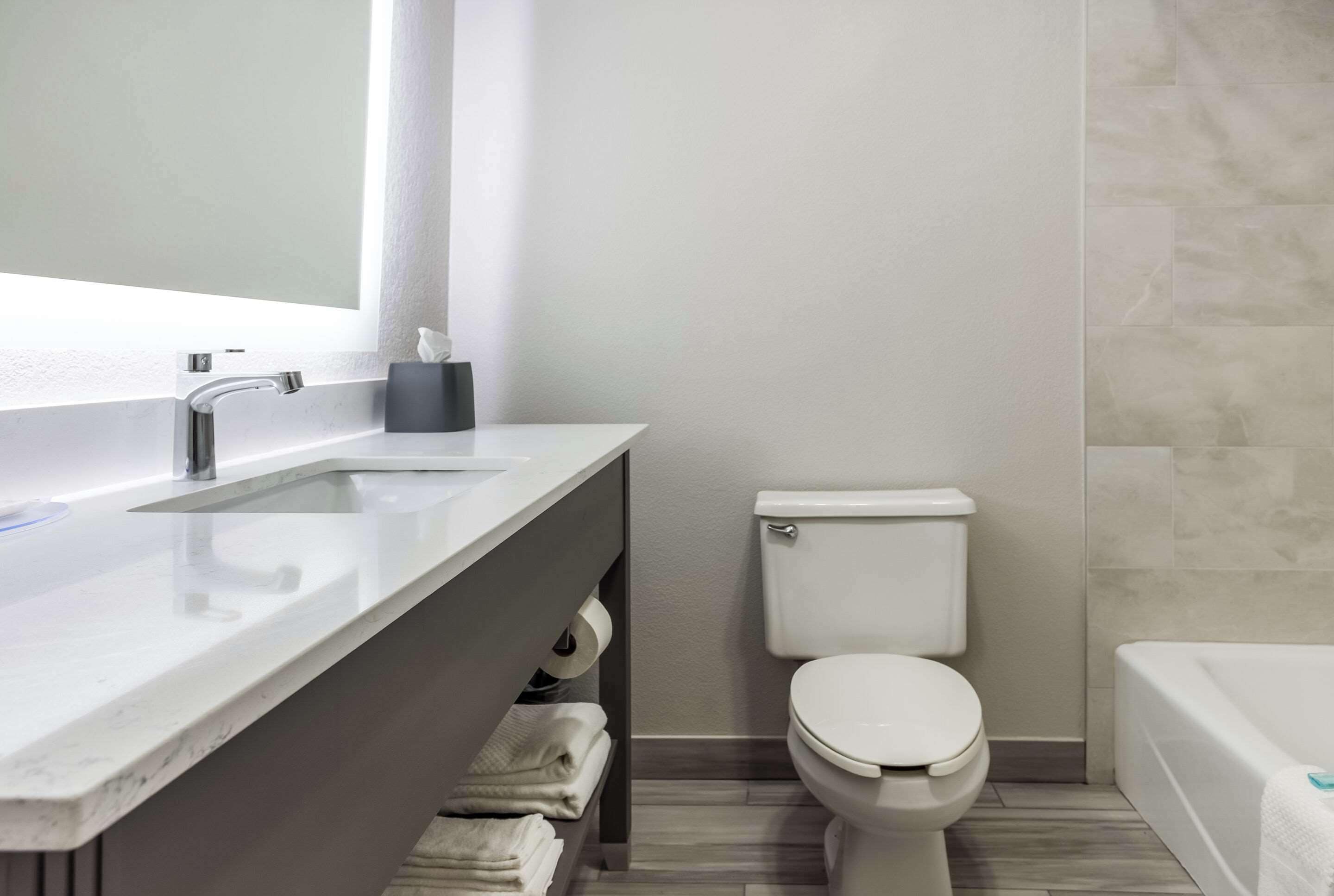 Une salle de bain moderne avec un lavabo blanc, un miroir et des toilettes, ainsi qu’une baignoire.