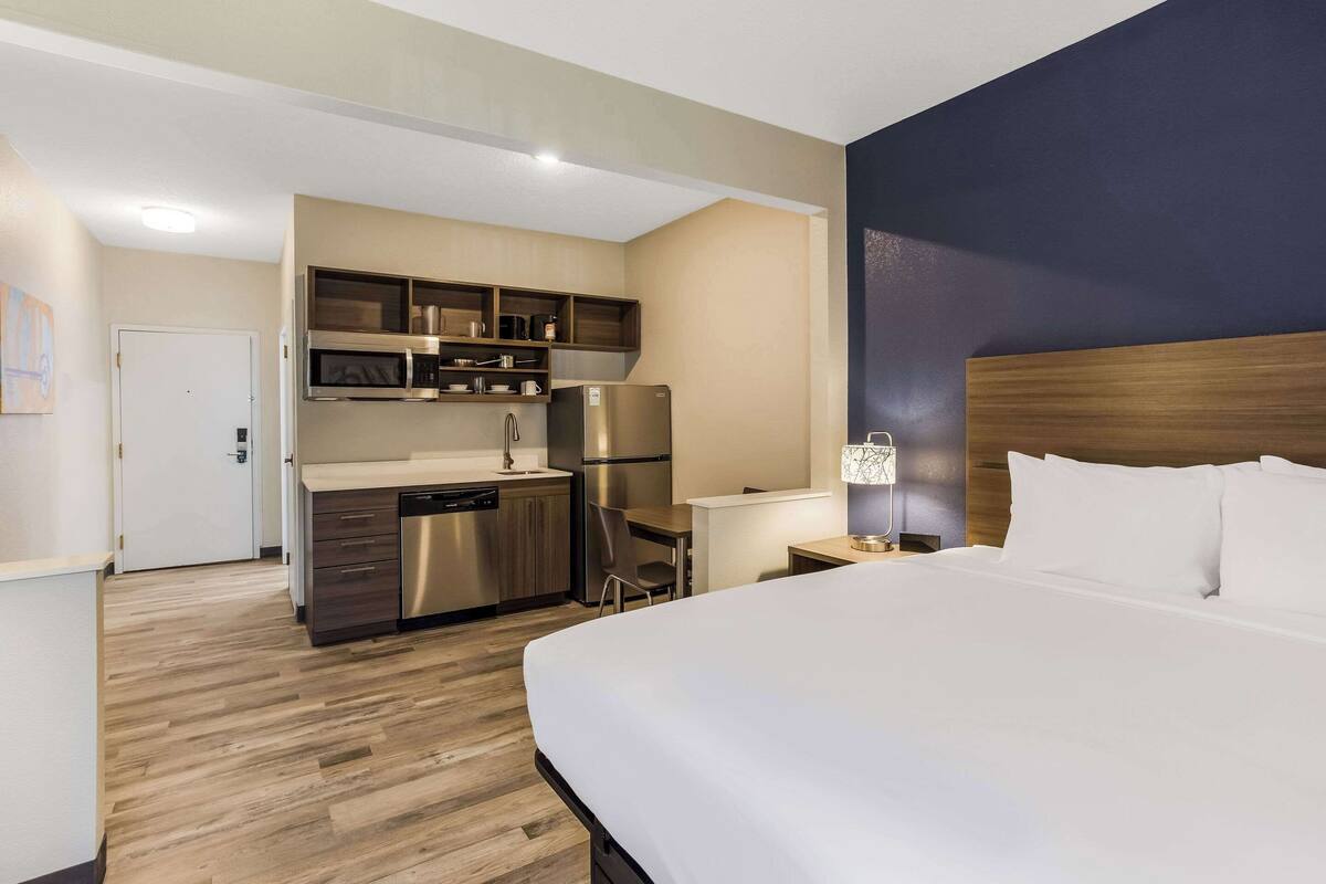 Une chambre d’hôtel comprenant un lit, un bureau, une kitchenette et une salle de bain.