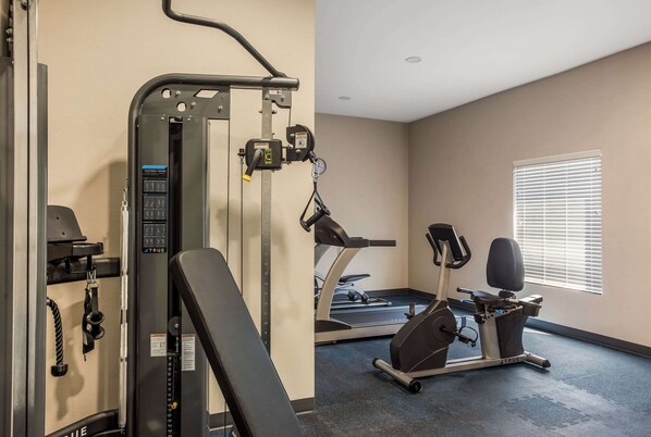 Un gimnasio con cinta de correr, máquinas de pesas y barra para dominadas.