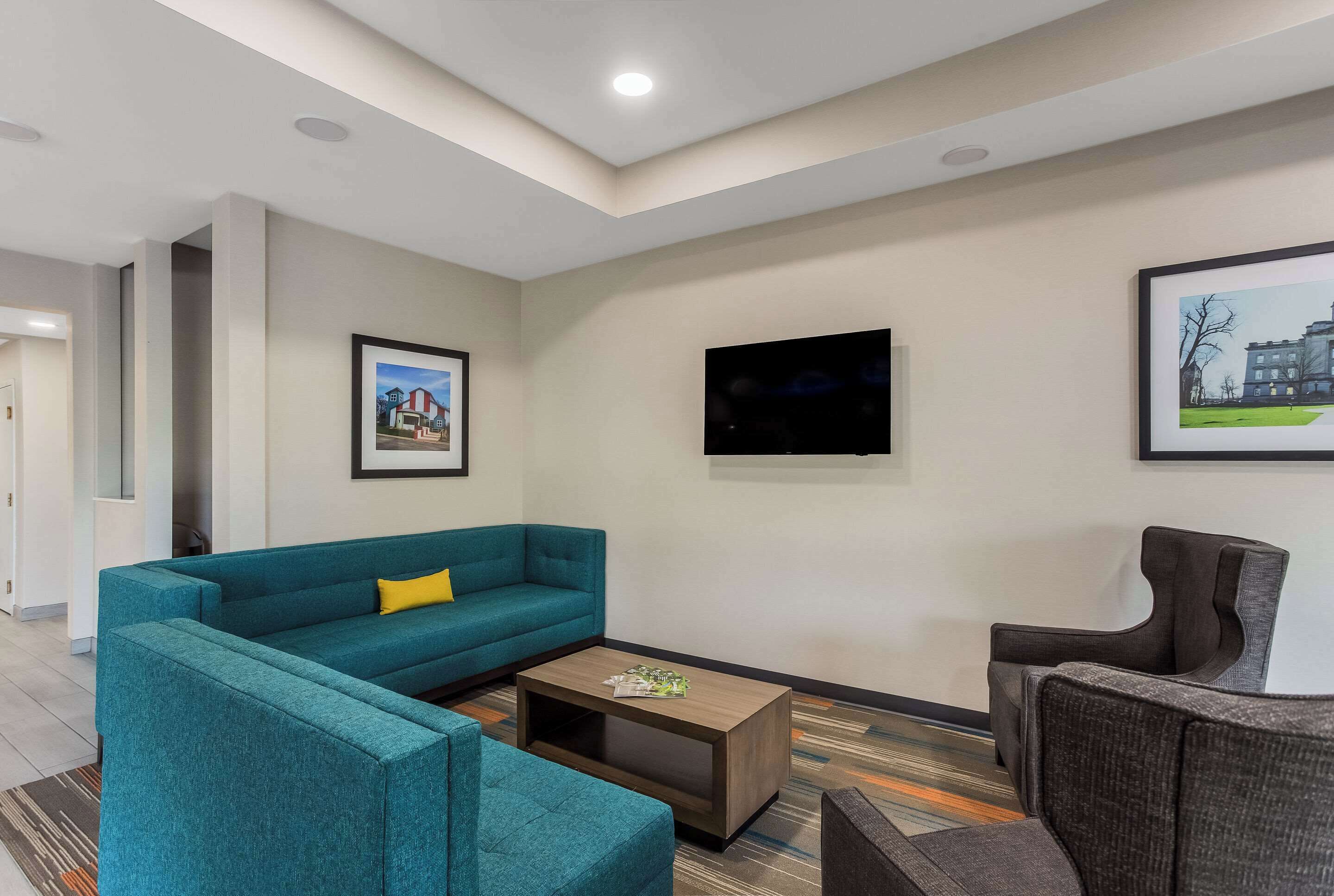 Una sala de estar moderna con un sofá color turquesa, una mesa de centro y un televisor montado en la pared.