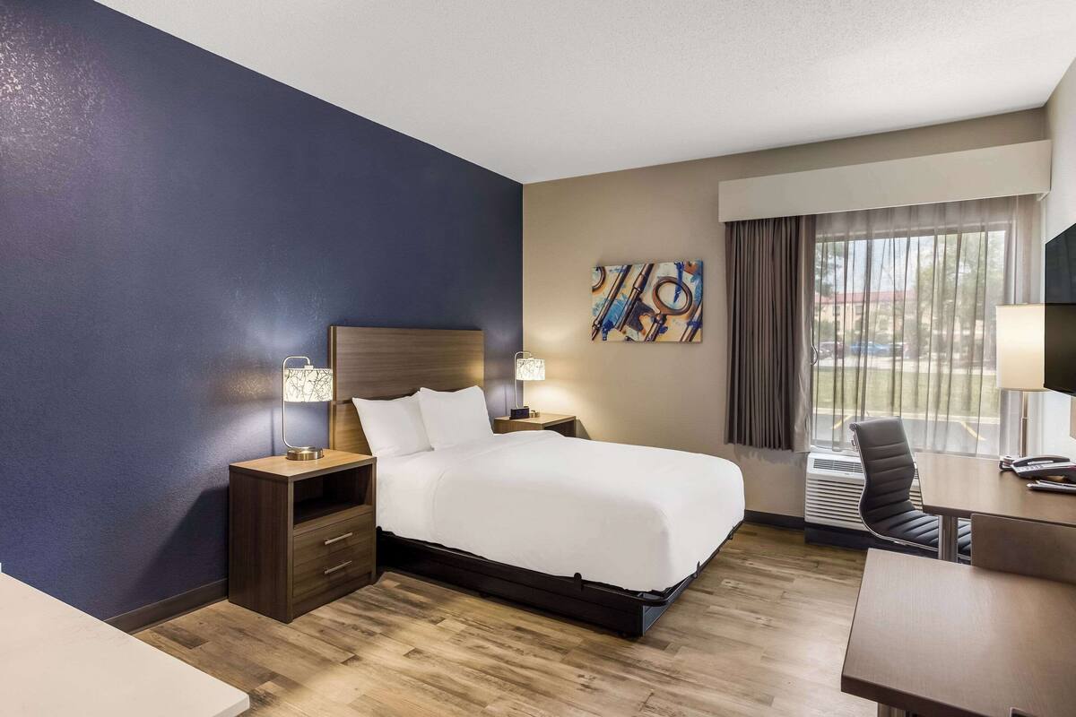 Une chambre d’hôtel avec un lit, des tables de chevet, un bureau et une chaise.