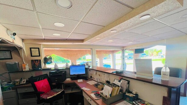 A small office with a desk, computer, and various office supplies.