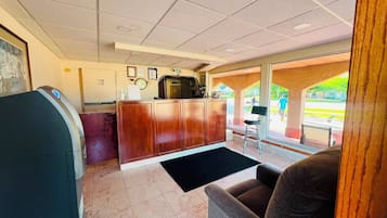 A reception area with a wooden desk, a black reception counter, a black rug, and a seating area with a brown chair.