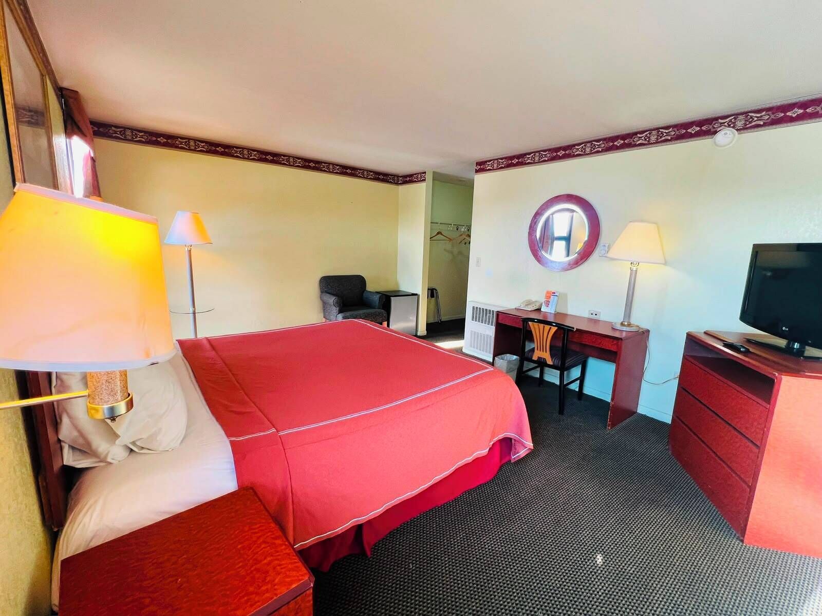 A hotel room with a bed, desk, chair, television, and two lamps.