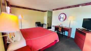 A hotel room with a bed, desk, chair, television, and two lamps.
