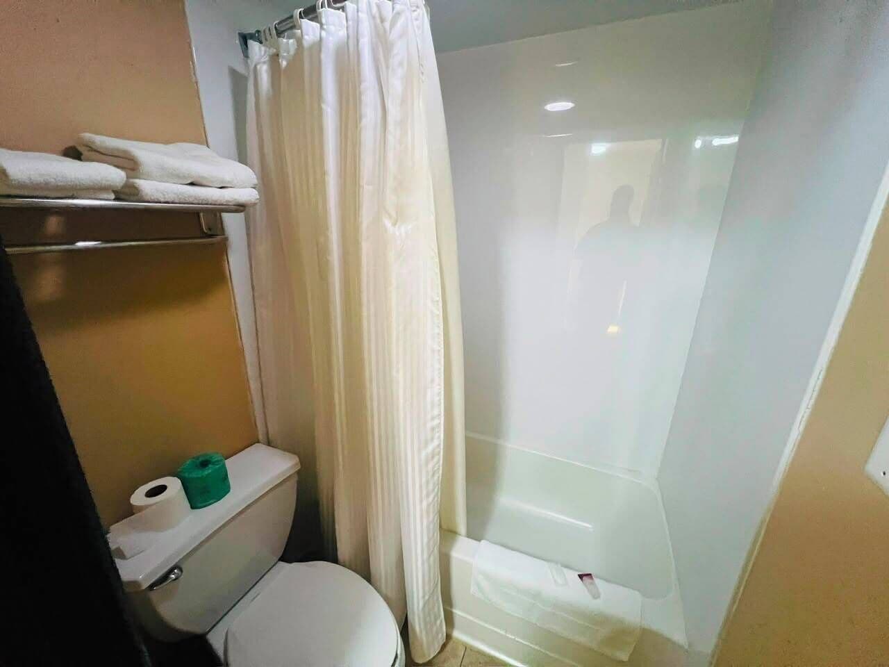 Ein Badezimmer mit Toilette, Duschkabine und Handtuchhalter mit Handtüchern.