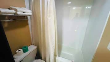 Ein Badezimmer mit Toilette, Duschkabine und Handtuchhalter mit Handtüchern.