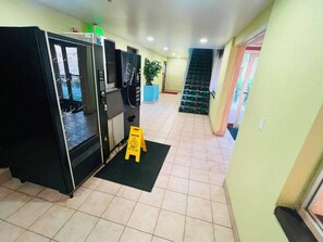 A hallway with a wet floor sign, a staircase, and vending machines. - Barrington Hotel Schaumberg Near I 90 (Barrington)