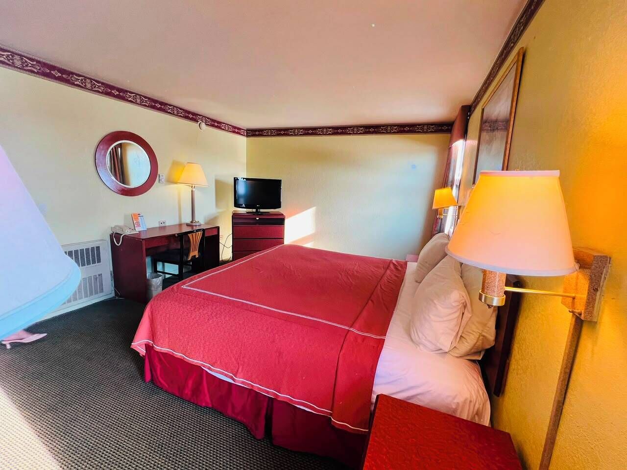 Ein Hotelzimmer mit einem Bett, einem Schreibtisch, einem Fernseher und einer Lampe.