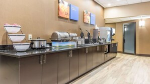 A buffet setup with various food items and appliances, including a waffle maker and a coffee machine. - Comfort Inn Alton near I-255 (Alton)
