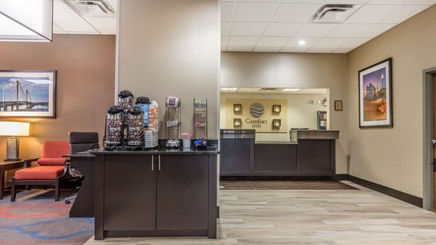 A hotel reception area with a counter, chairs, and a framed picture on the wall. - Comfort Inn Alton near I-255 (Alton)