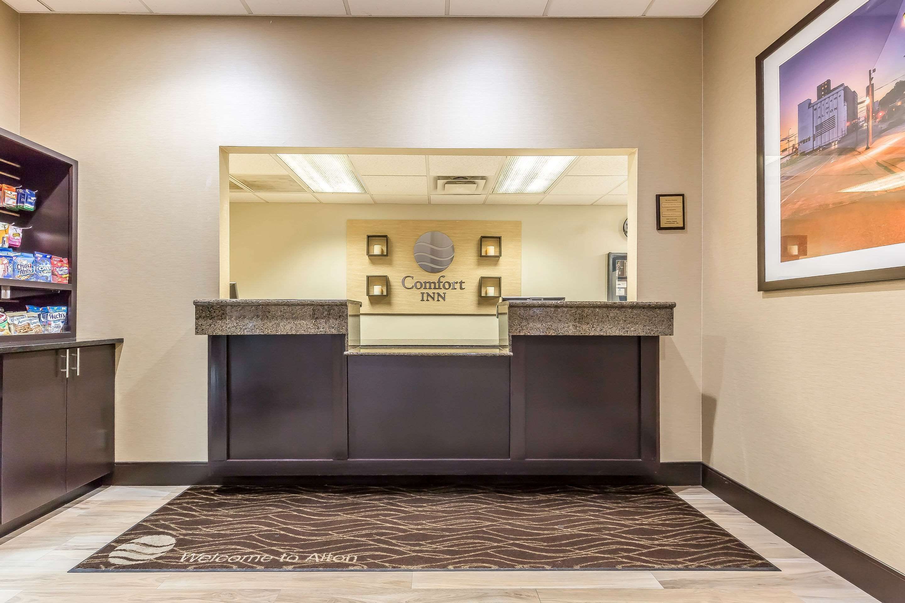 A reception area with a Comfort Inn sign, a reception desk, a framed picture on the wall, and a welcome mat.