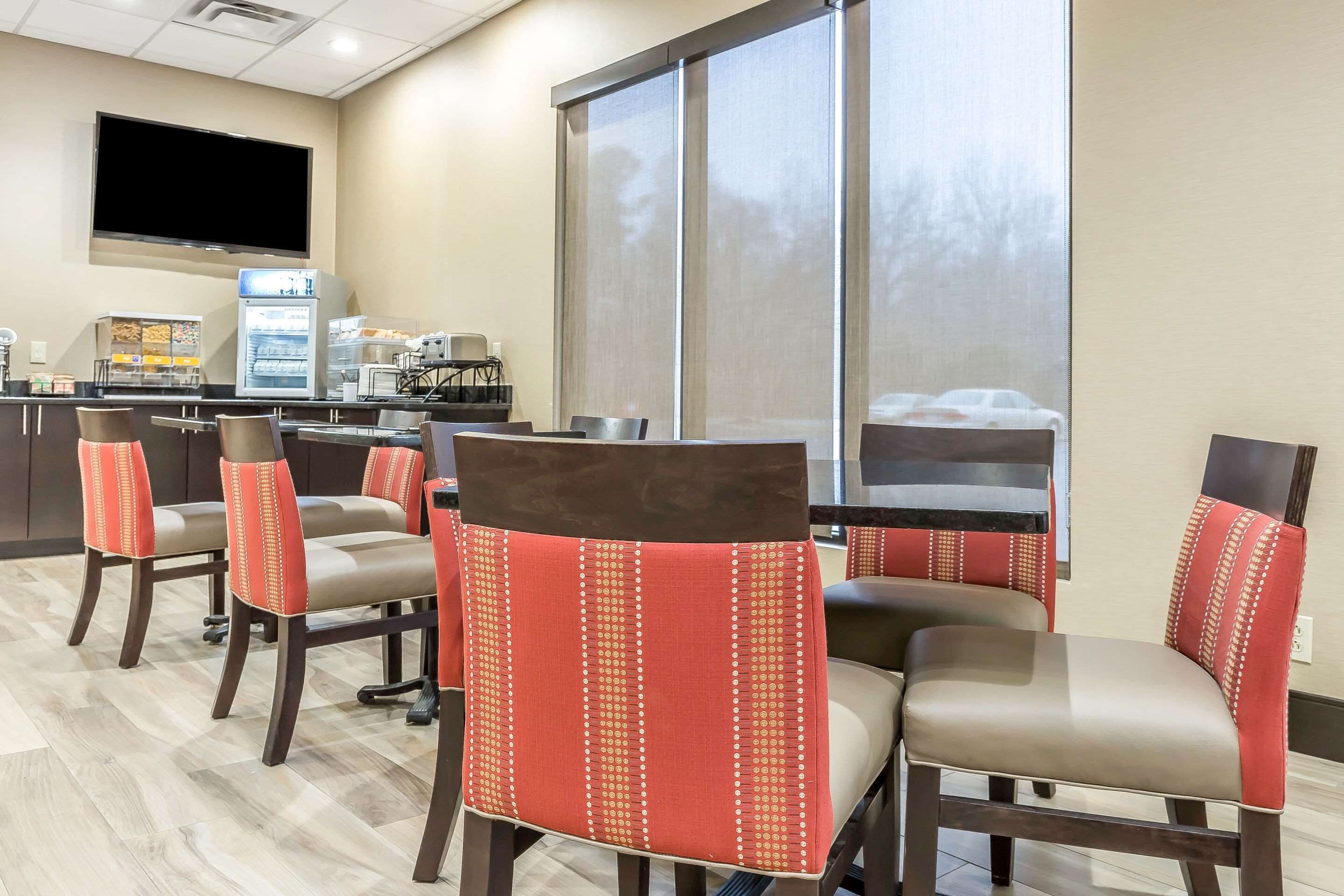 A restaurant with high-backed chairs, a flat-screen TV, and a refrigerator.