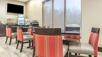 A restaurant with high-backed chairs, a flat-screen TV, and a refrigerator.