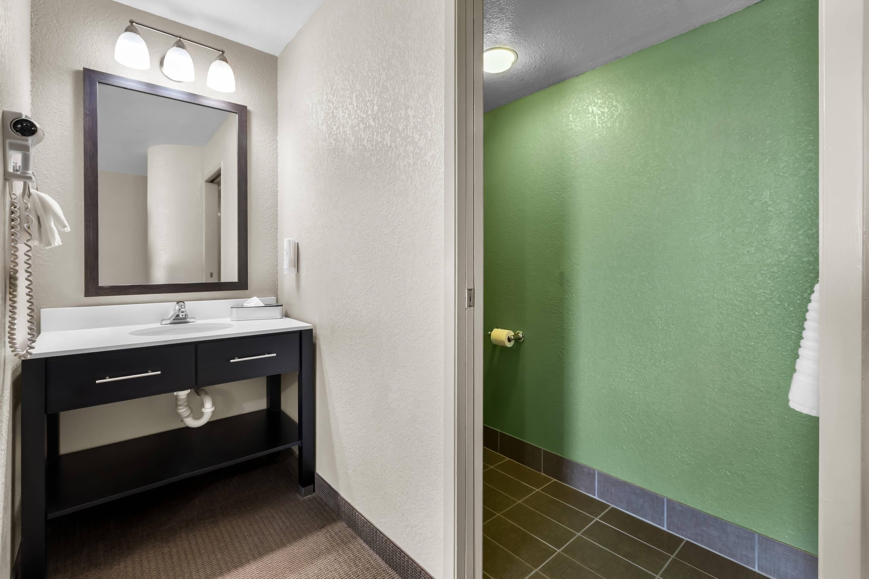 A bathroom with a sink, mirror, towel rack, and a green wall.