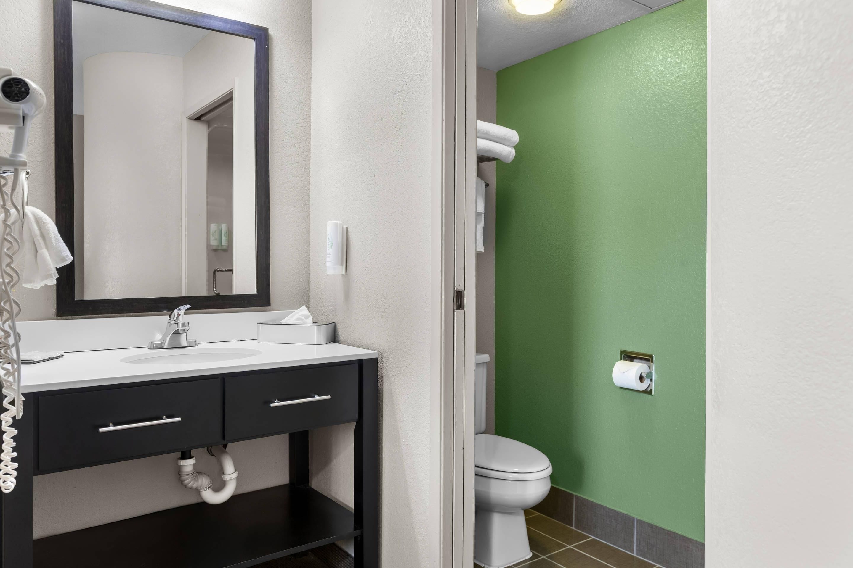 A bathroom with a white sink, a mirror, a towel rack, and a toilet.
