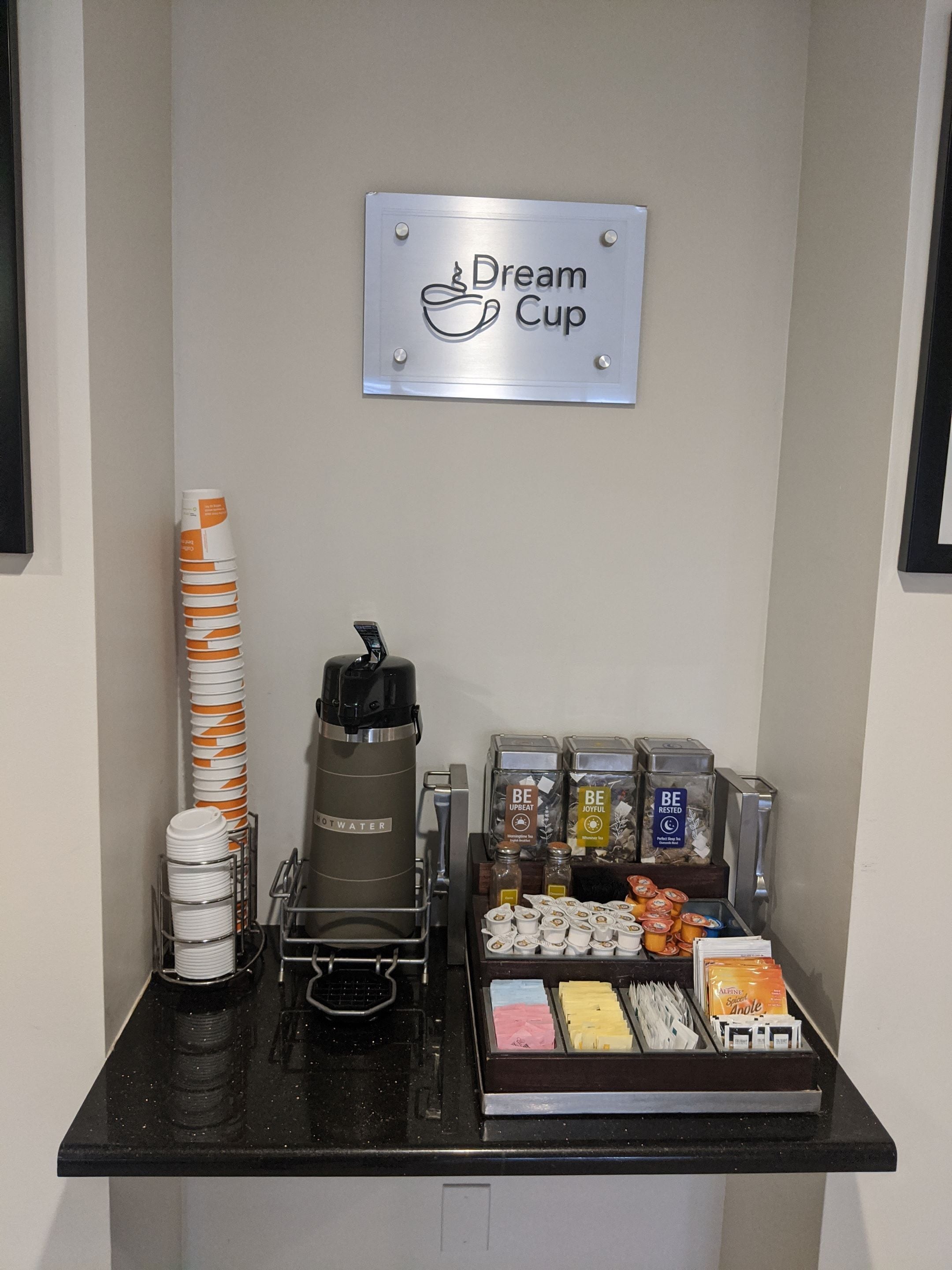 A coffee station with a coffee machine, disposable cups, and a sign that reads "Dream Cup".