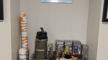 Una estación de café con una máquina de café, vasos desechables y un letrero que dice 'Dream Cup'.