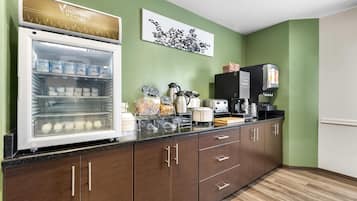 A breakfast bar with a refrigerator stocked with beverages, a coffee machine, and a variety of food items.