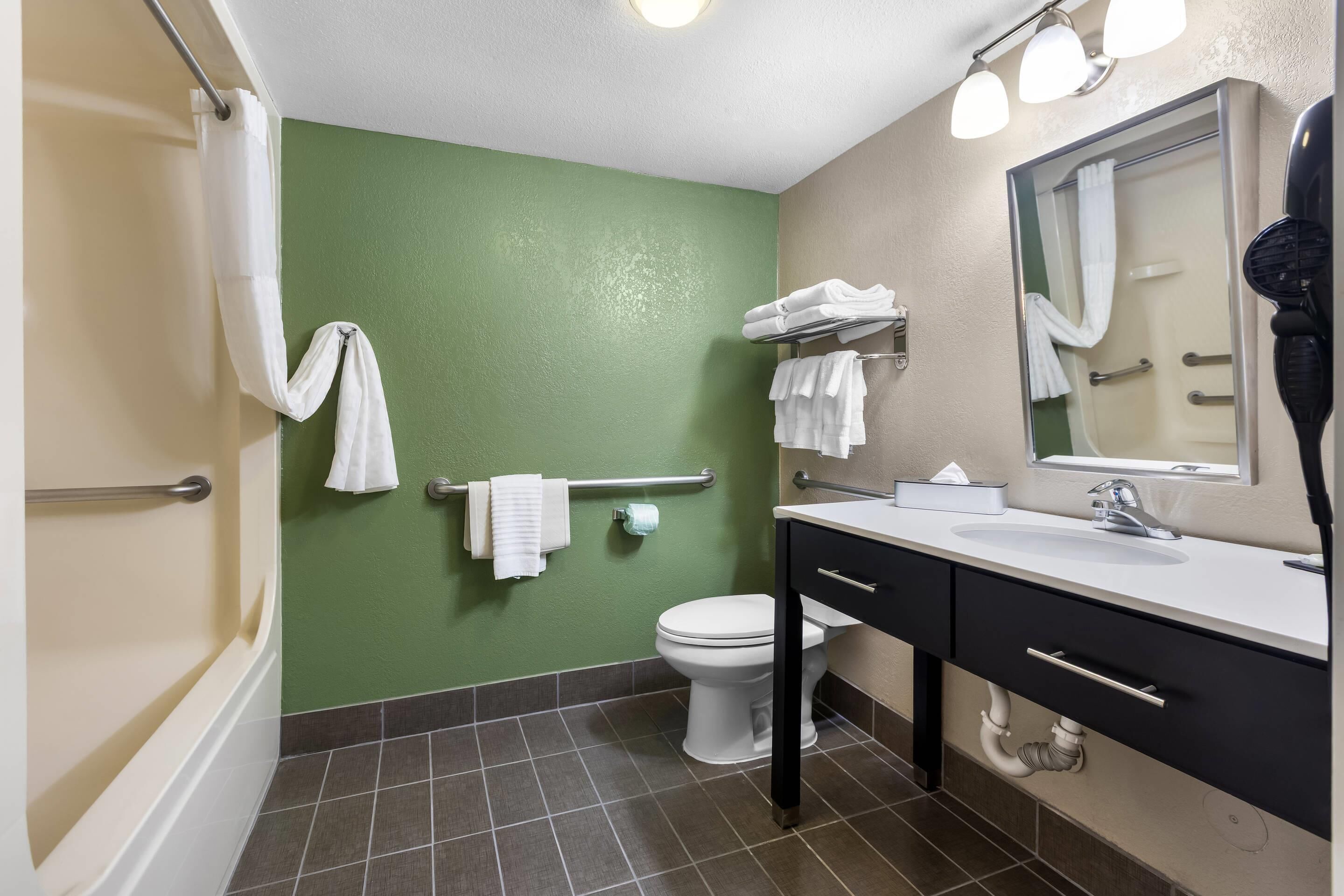 A bathroom with a green wall, white toilet, and a sink with a mirror.