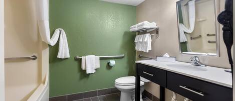 A bathroom with a green wall, white toilet, and a sink with a mirror.