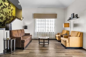 A modern living room with a brown sofa, yellow armchairs, a round coffee table, and a floor lamp.