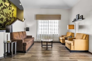 Una sala de estar moderna con un sofá marrón, sillones amarillos, una mesa de centro redonda y una lámpara de pie.