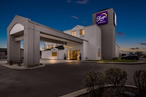A Sleep Inn hotel with a modern architectural design, featuring a prominent entrance with a covered walkway and a large illuminated sign.